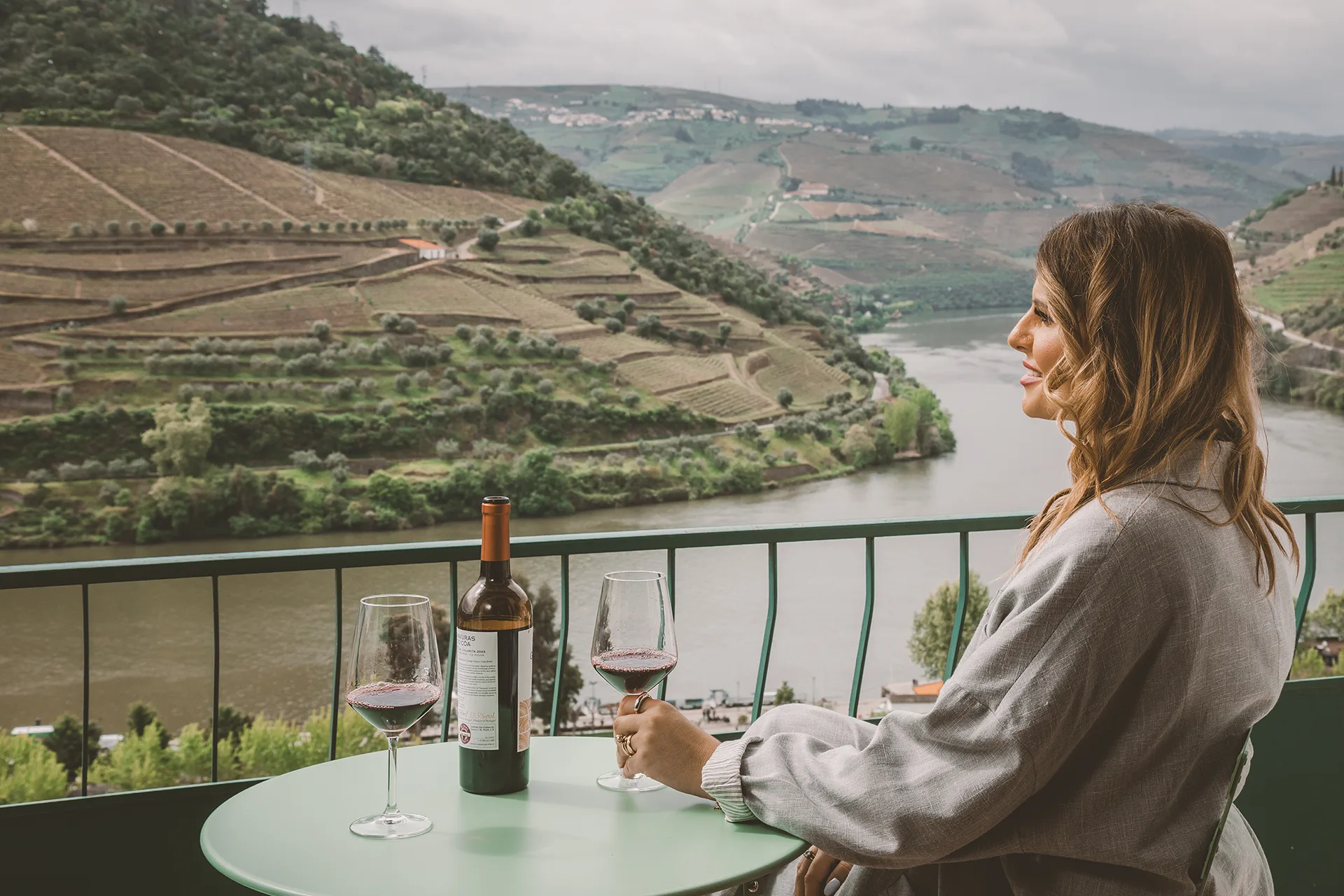 Mulher a provar vinho na varanda com vista para o rio Douro na Douro Panorama Valley