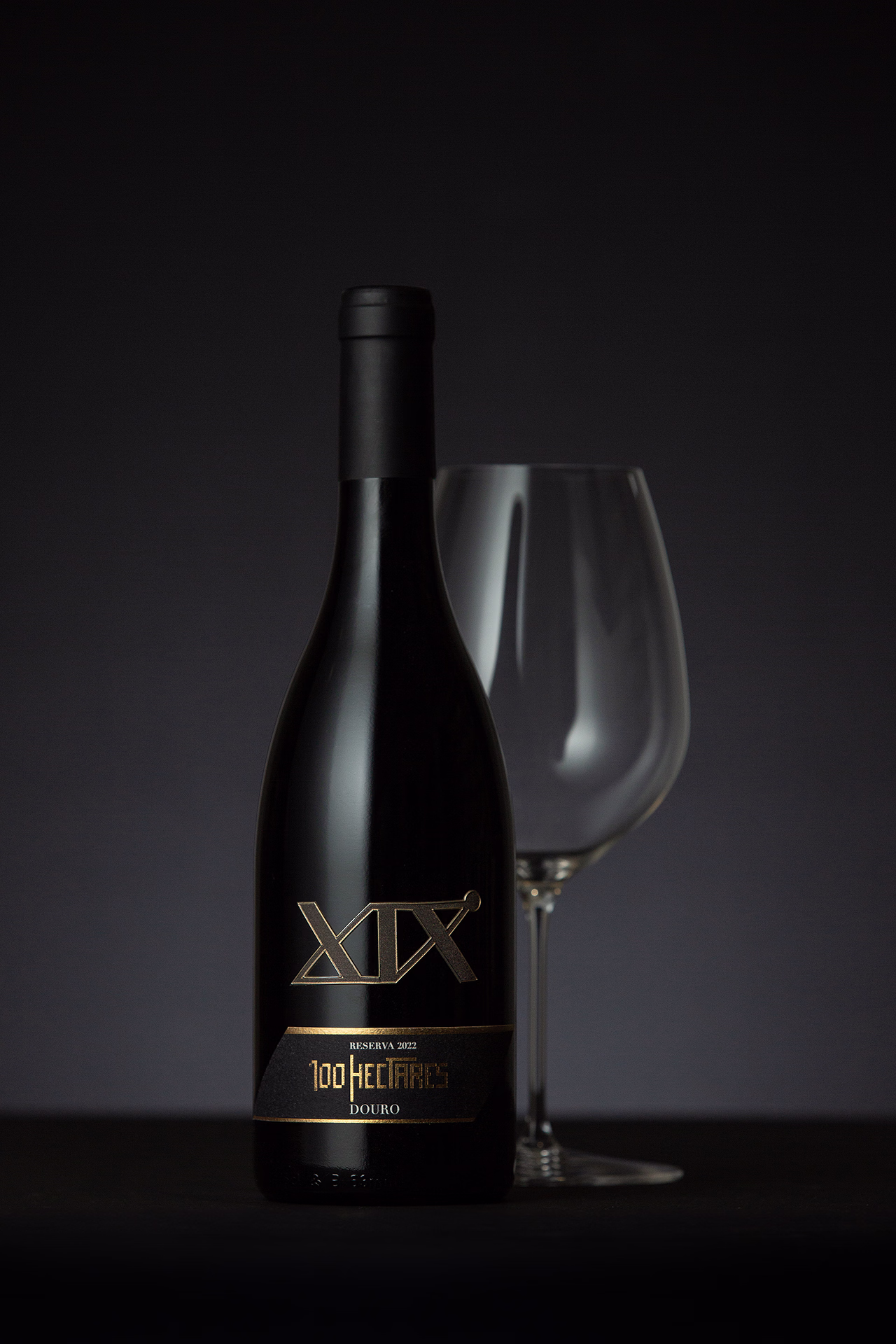 Fotografia profissional do vinho XIX Reserva 2022 100Hectares do Douro destacando garrafa premium com iluminação de estúdio e composição elegante fotografia de vinho Douro fotografia de produto vinho fotografia profissional vinhos vinho Douro Reserva fotografia comercial vinho fotografia garrafa vinho premium
